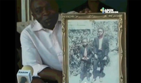 Léon Raoul Minko Mengere, petit-fils de Léon Mba, exhibant une photo de lui avec Ali Bongo à 8 ans. © Capture d’écran/Gabonreview