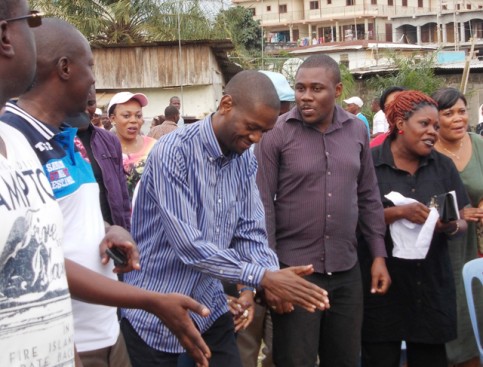 Eloi Nzondo (chemise à rayures) en communion avec les habitants du quartier, en septembre 2013. © Gabonreview
