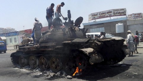 Des personnes se tiennent sur un char calciné, le 29 mars à Aden.REUTERS/Stringer