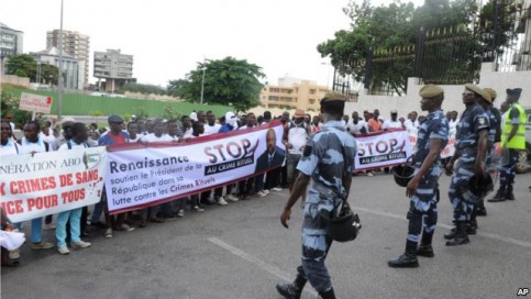Une foule de gens qui protestent contre les meurtres rituels portent des banderoles "Stop crime rituel; soutenir le président dans sa lutte contre les crimes rituels" à Libreville, le 11 mai 2013.
