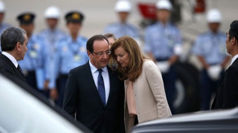 French President Hollande talks with his companion Trierweiler as security officers stand guard upon their arrival at Haneda airport in Tokyo